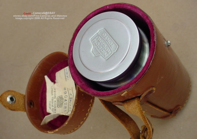 An original leather case with  a chrome body cap on a 135mm Nikkor lens