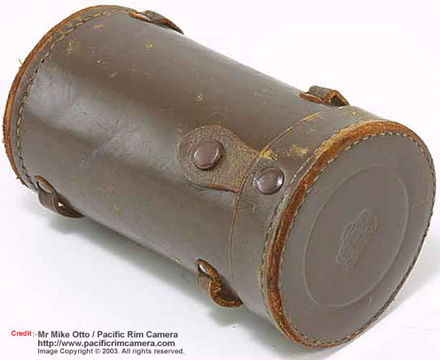 An original leather case with  a chrome body cap on a 135mm Nikkor lens